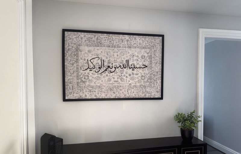 Hasbunallahu wa ni’mal wakeel, framed in black, on a hallway wall above a console