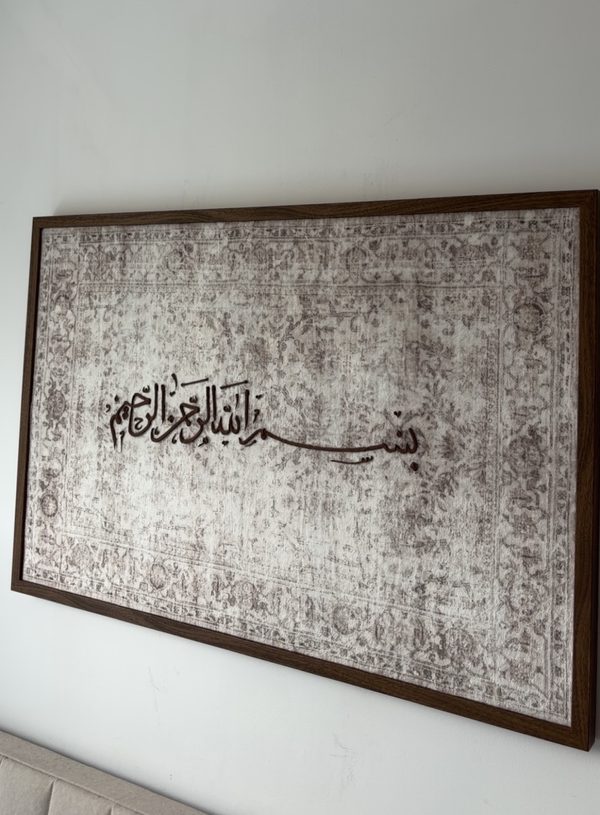 Bismillah ir-Rahman ir-Rahim in a walnut-tone frame on a living-room wall above a sofa